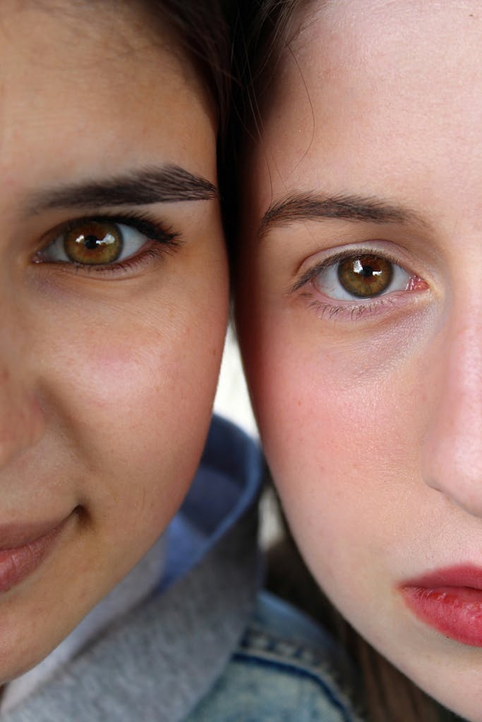 An intimate, close-up vertical portrait of two young women showcasing diversity and beauty.
